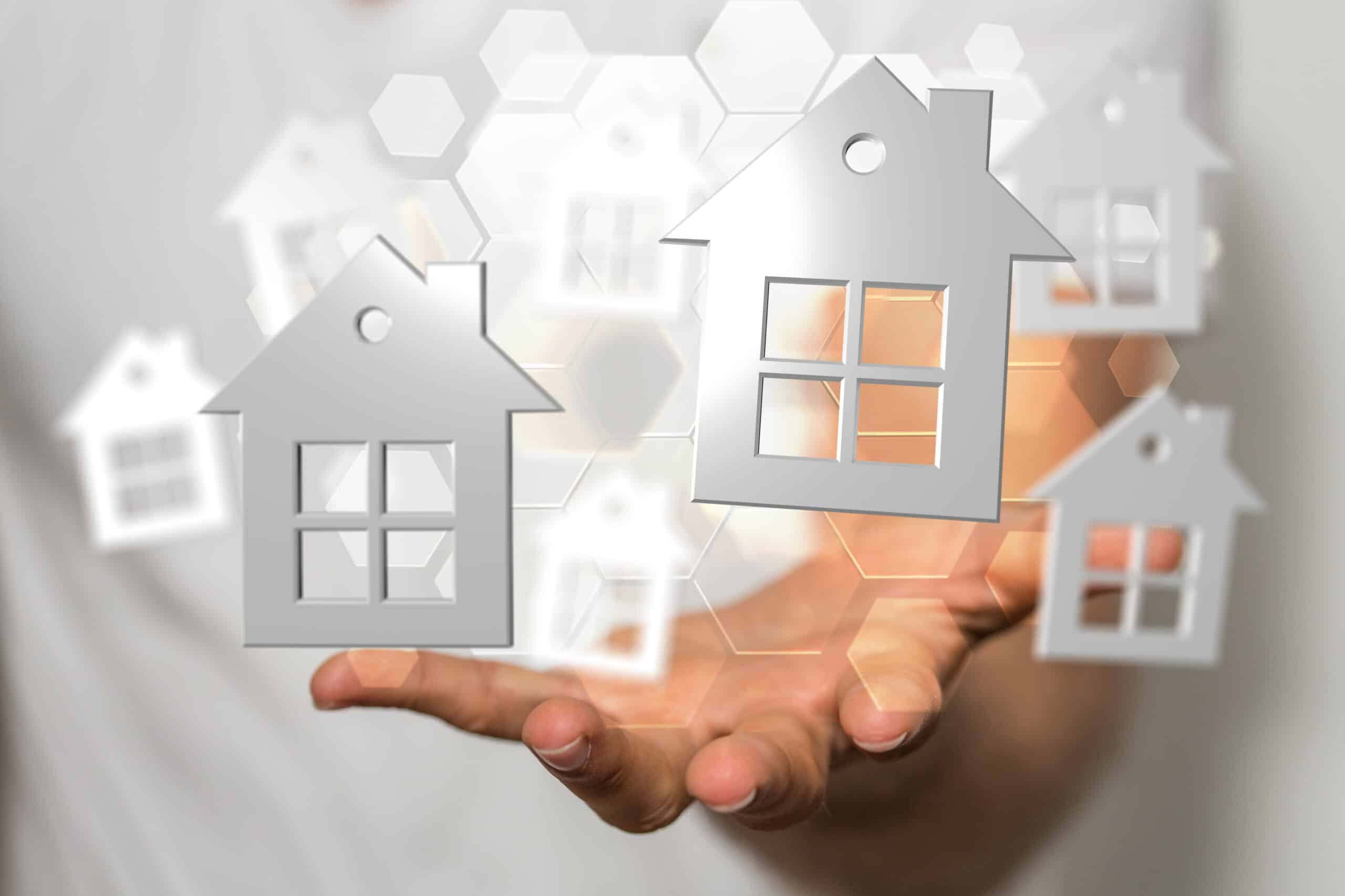 Hand hält digitale Haussymbole – symbolischer Einstieg in die Immobilienbranche