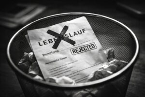 Abgelehnter Lebenslauf liegt zerknüllt in einem Papierkorb – Symbol für den Mythos des perfekten Lebenslaufs im Recruiting